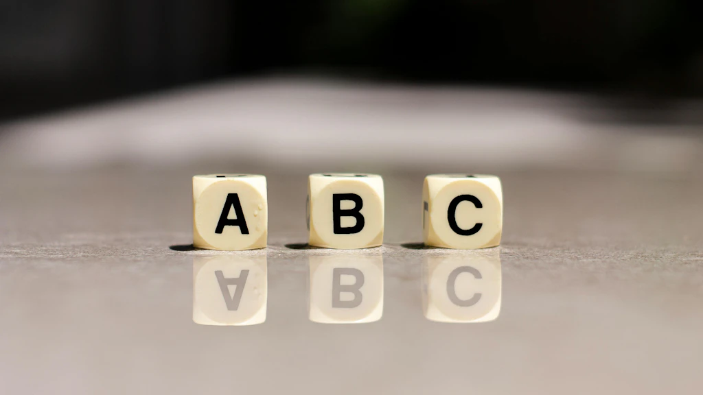 Trois cubes portant les lettres A, B et C sont posés sur une surface grise.