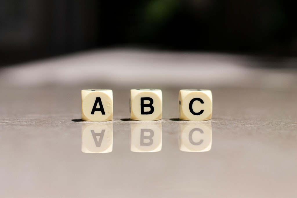 Trois cubes portant les lettres A, B et C sont posés sur une surface grise.