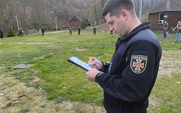 Un homme prend des notes sur un champ d’exercice.