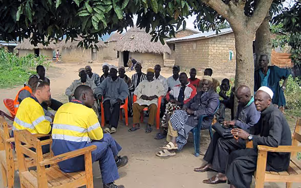 Quelque part en Guinée : réunis sous un cadre, les cadres d’une entreprise d’extraction minière discutent de l’impact de leurs activités avec les représentants d’un village.