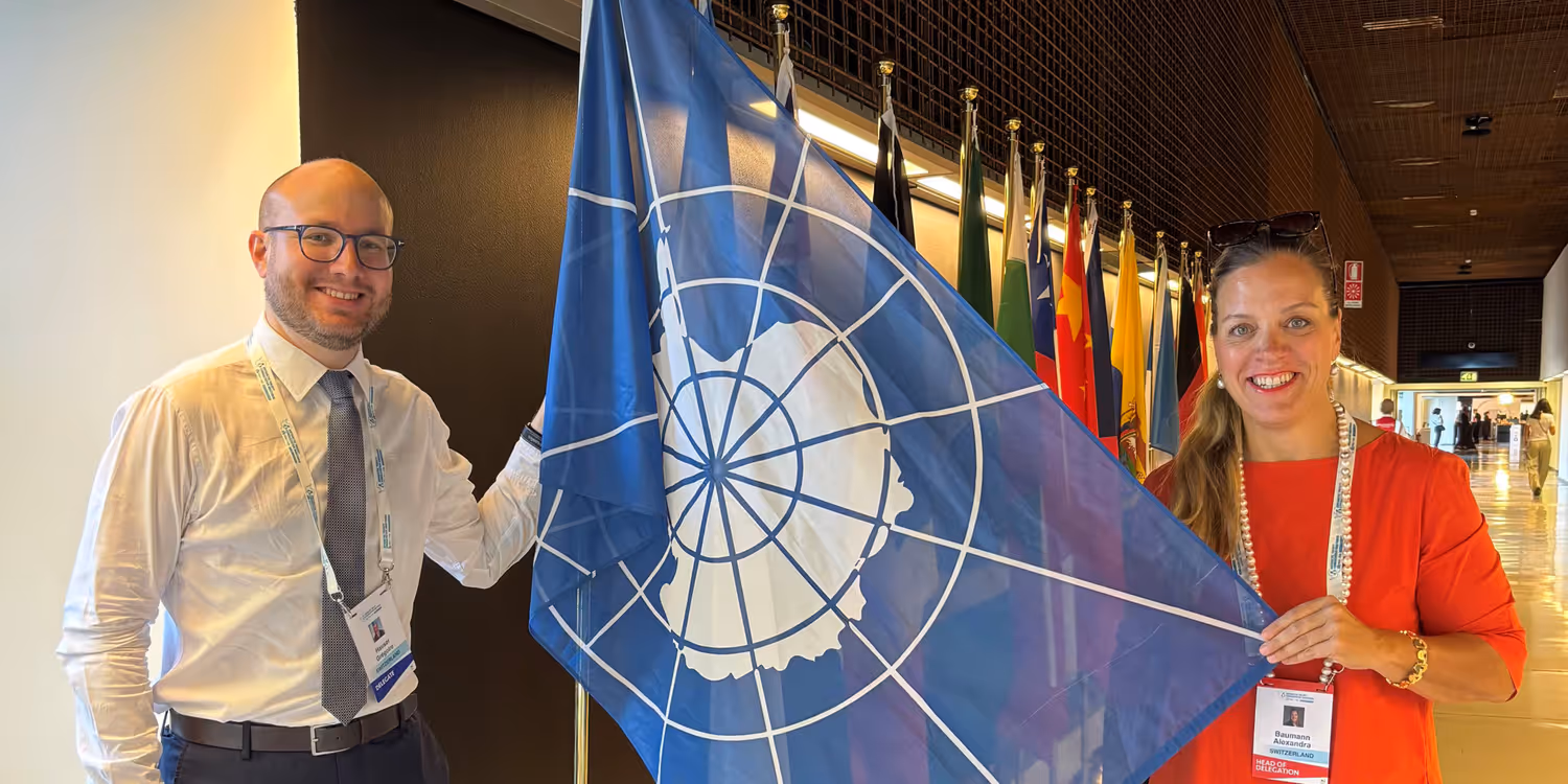Grégoire Hauser et l'ambassadrice Alexandra Baaumann, entre eux un drapeau représentant la région polaire.