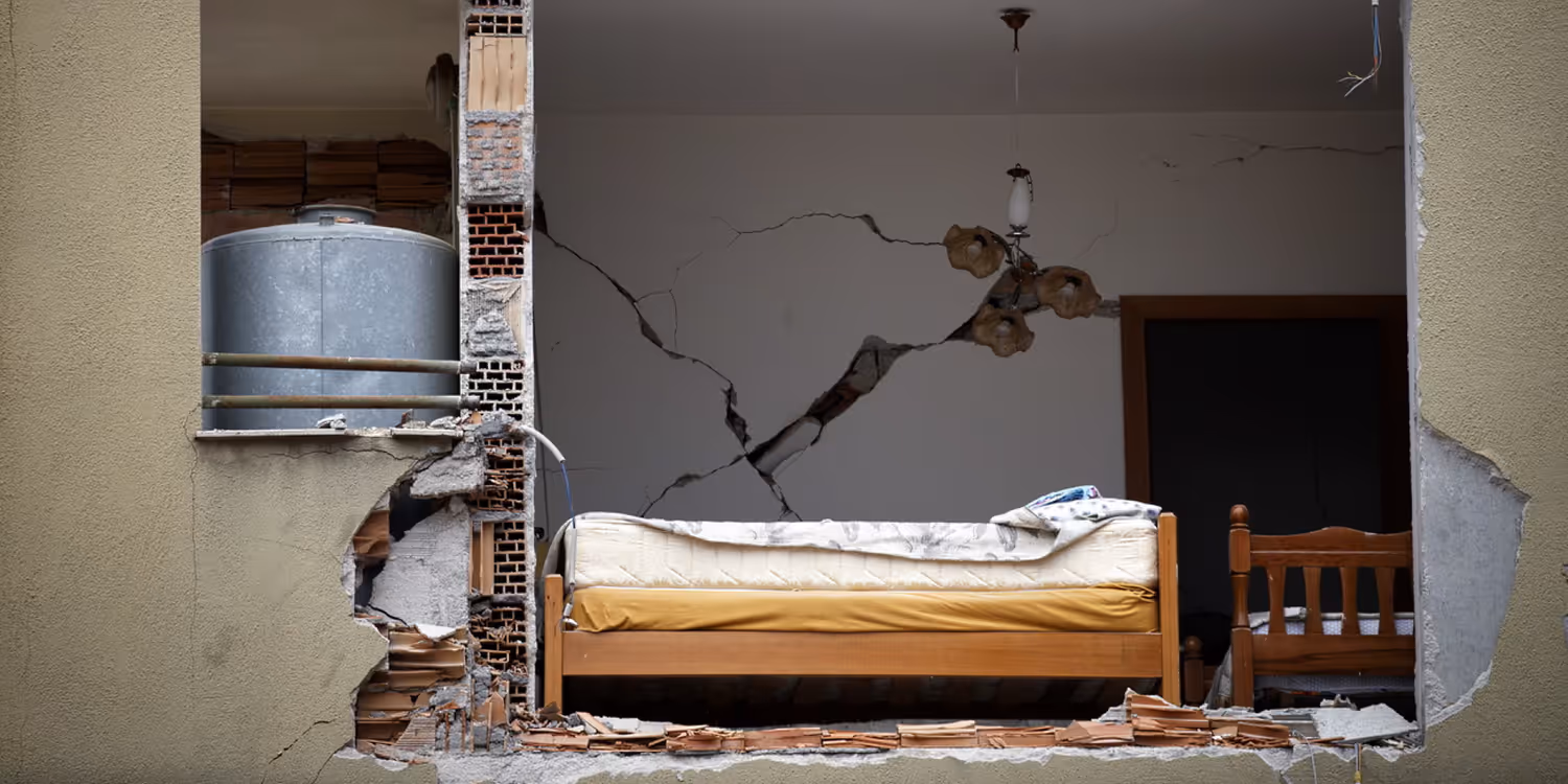 Immeuble d’habitation dont la façade a été éventrée. Le trou provoqué par le séisme laisse entrevoir l’intérieur d’une chambre à coucher.