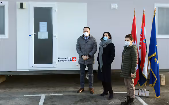 In piedi davanti a un’unità abitativa l’ambasciatrice svizzera Emilija Georgieva, la segretaria di Stato Irena Petrijevčanin Vuksanović (Ministero degli Interni) e il segretario di Stato Zdenko Lucić (Ministero degli Affari Europei ed Esteri).