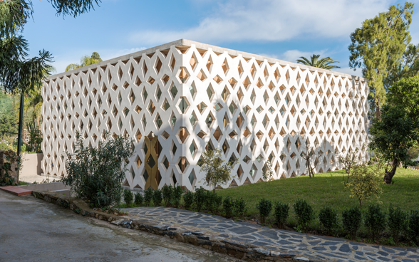 L’Ambasciata di Svizzera ad Algeri vista dall’esterno. L’edificio, di un bianco splendente, ha la forma di un parallelepipedo rettangolare. La facciata è costituita da numerose travi che si incrociano tra loro formando una sorta di grande griglia.