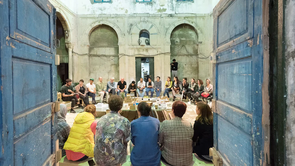 Un gruppo di giovani siede in cerchio nel cortile interno di un edificio in occasione del festival Dream City di Tunisi. 