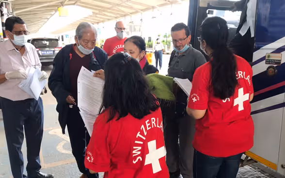 I passeggeri scendono da un autobus all'ingresso dell'aeroporto di Goa, in India. Vengono accolti dai collaboratori delle rappresentanze svizzere locali.