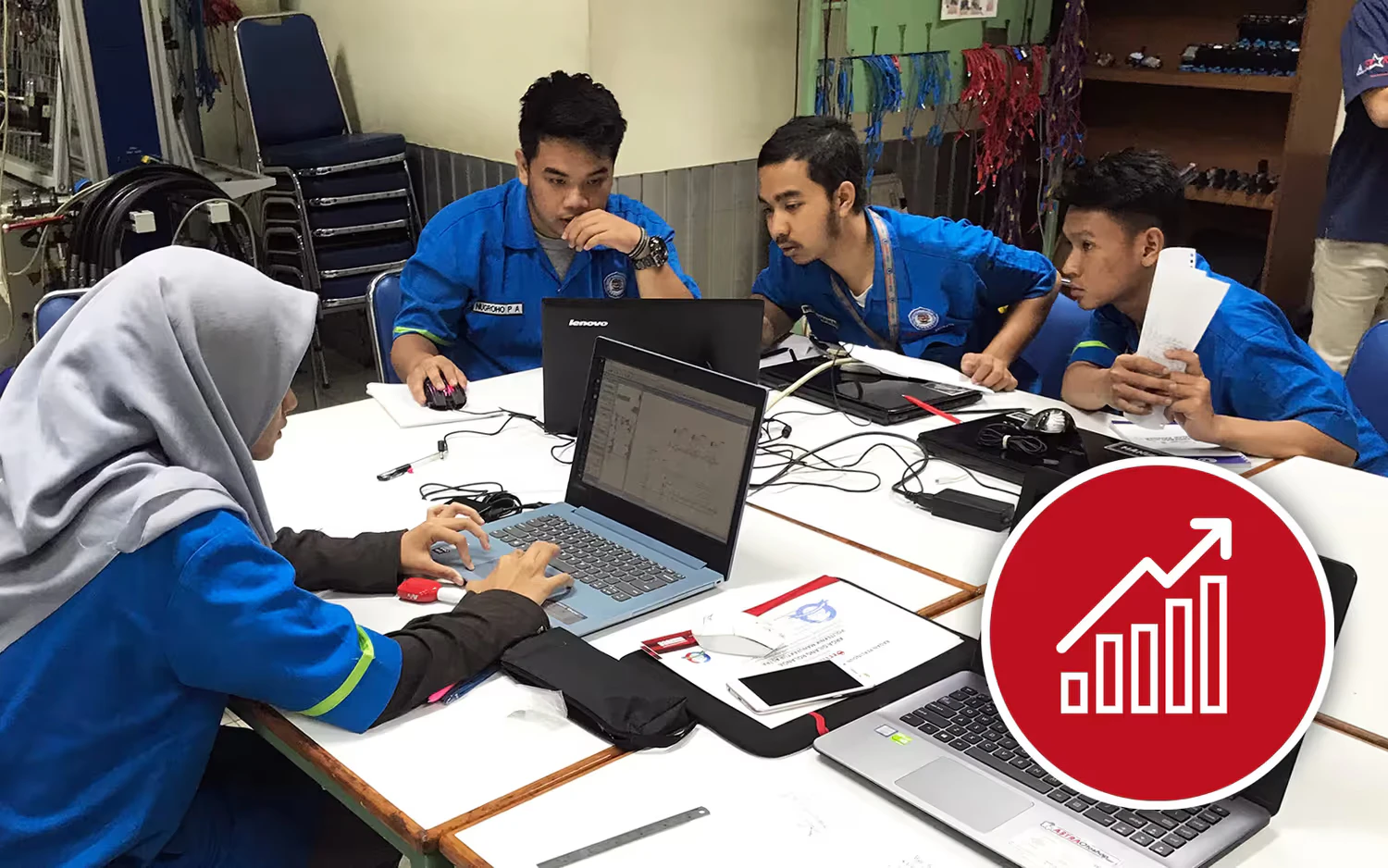 Una ragazza e tre ragazzi lavorano al computer indossando una divisa blu.