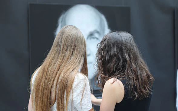 Due giovani allieve guardano un cartellone dell’esposizione.