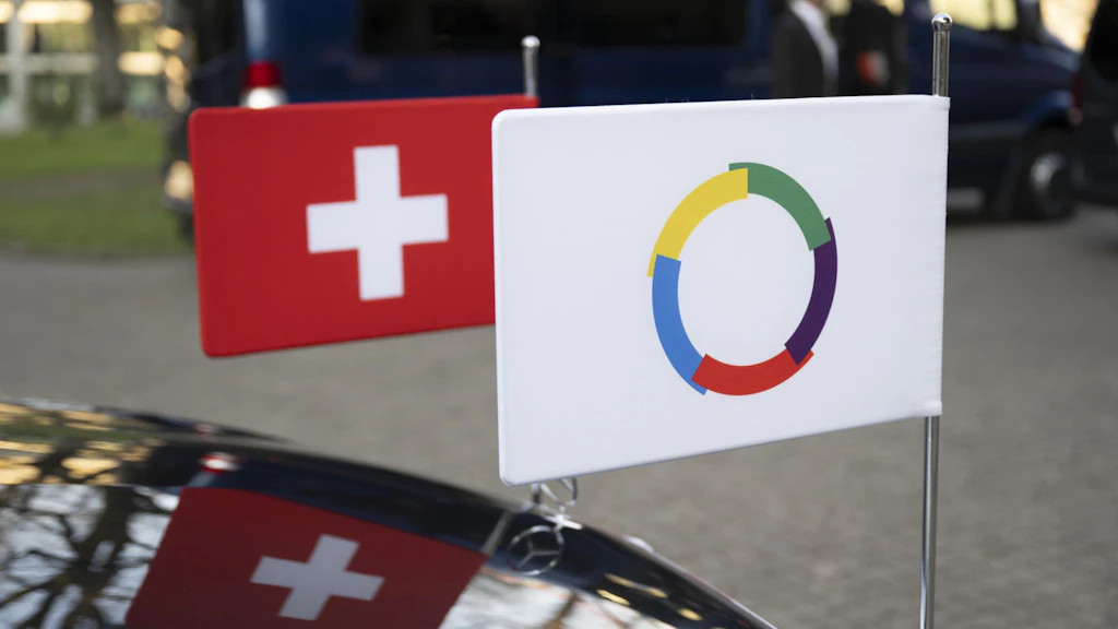 L'immagine mostra le bandiere dell'Organizzazione internazionale della Francofonia (OIF) e della Svizzera appese a un'automobile.