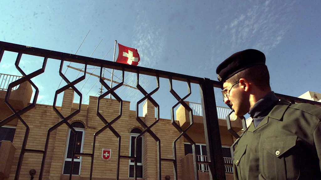 Una guardia della polizia irachena davanti ai cancelli dell'ex ambasciata svizzera a Baghdad.