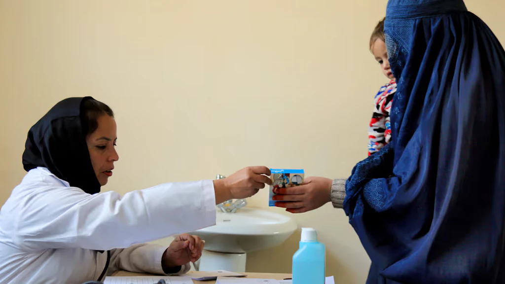 Una madre con suo figlio in braccio riceve una cura da un dipendente dell'ospedale di Kabul/Afghanistan. 