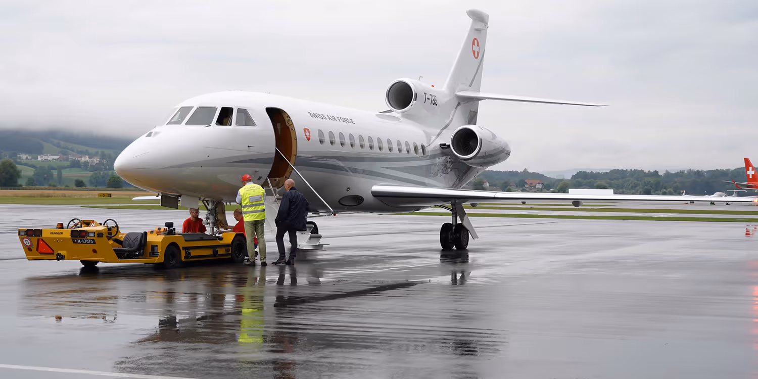 Due uomini davanti a un jet sulla pista dell’aeroporto di Berna-Belp.