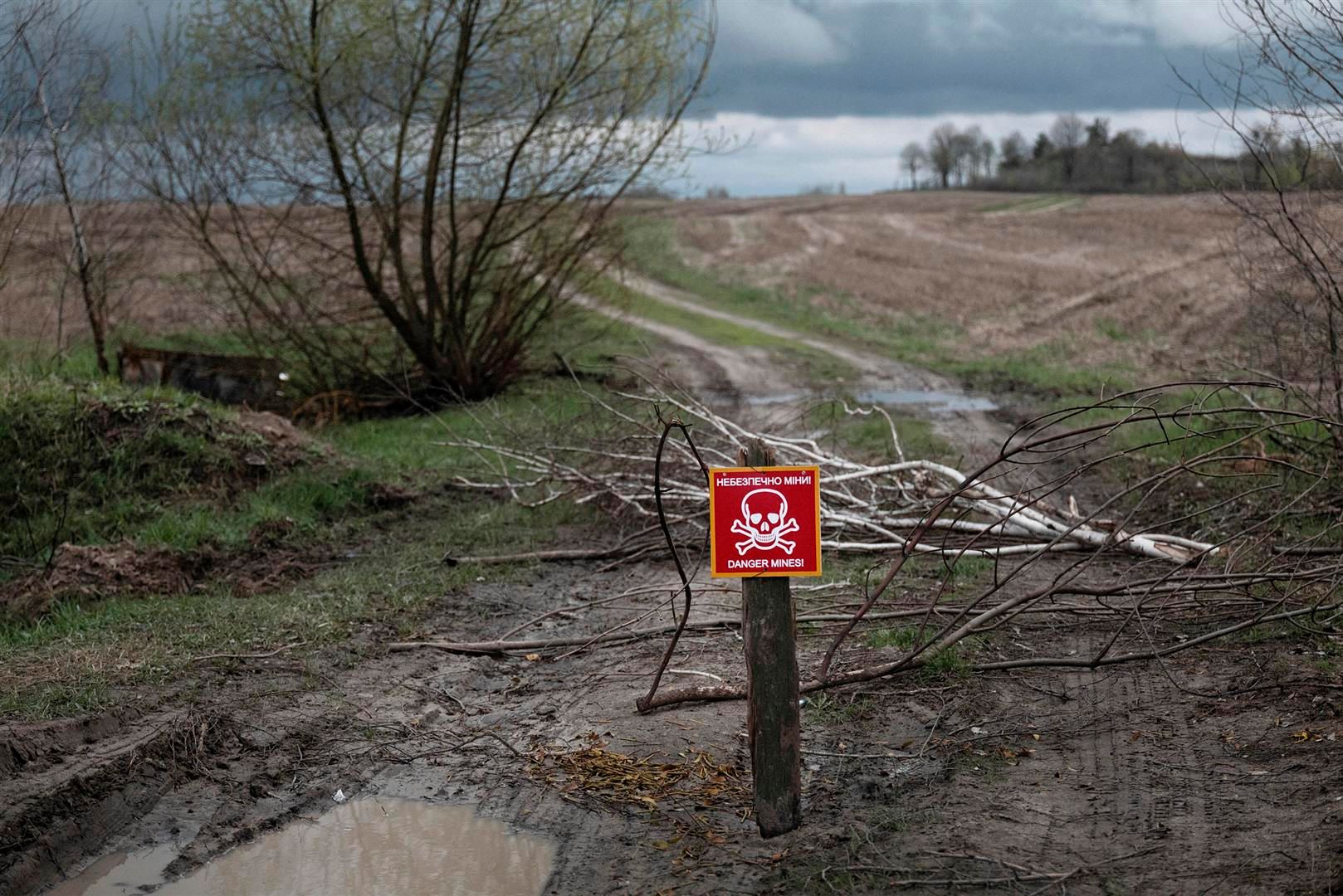 Un cartello rosso con un teschio, posto su un sentiero, avverte del pericolo di un campo minato.
