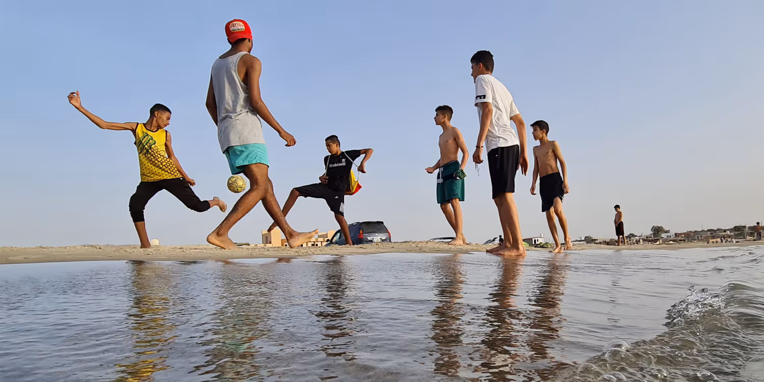 Alcuni giovani giocano a calcio su una spiaggia di Garabulli, a circa 70 km dalla capitale Tripoli.