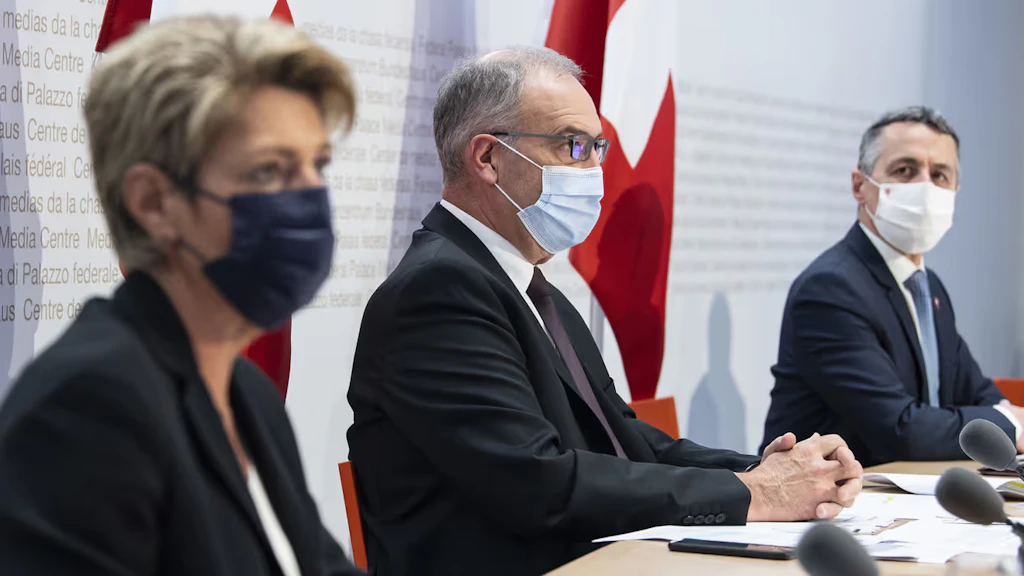 Il presidente Guy Parmelin, il consigliere federale Ignazio Cassis e la consigliera federale Karin Keller-Sutter siedono sul podio del Centro media a Berna.