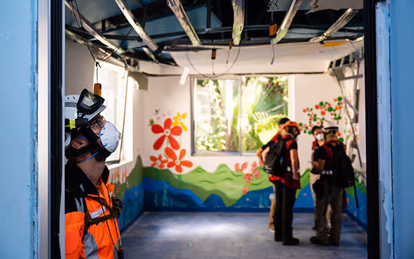 Un esperto dell’Aiuto umanitario della Confederazione osserva il soffitto danneggiato di un ospedale.