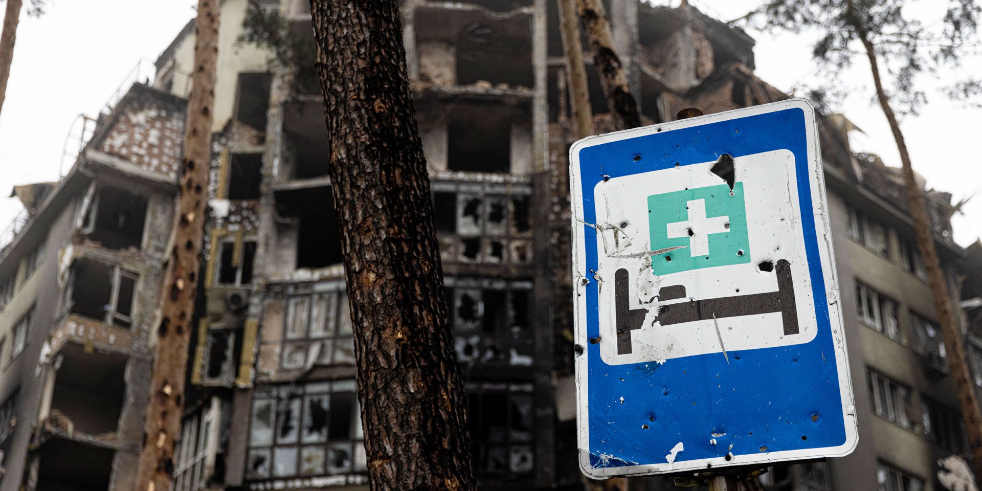 Edifici distrutti e un cartello che indica un ospedale.