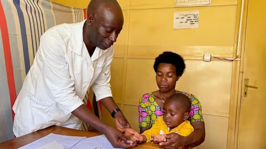Un medico visita un bambino tra le braccia di sua madre.