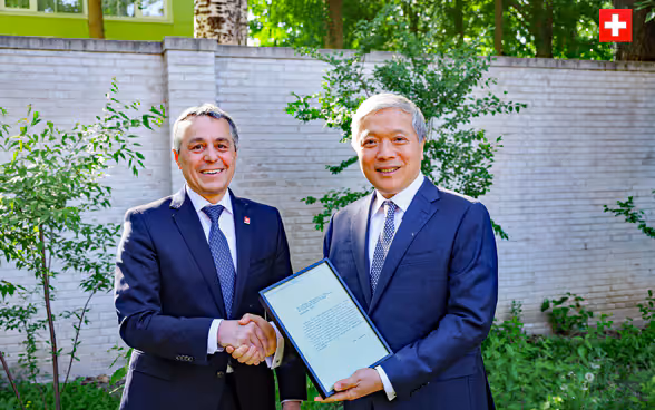 Il consigliere federale Ignazio Cassis e l'ambasciatore Zhu Liying si stringono la mano. 