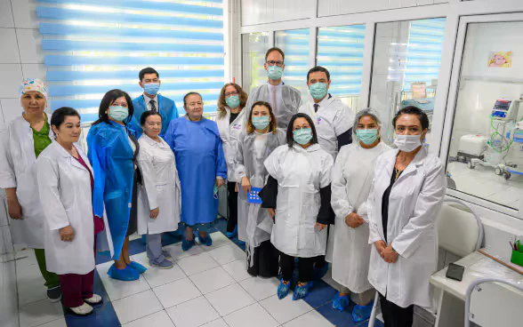 Gruppo di uomini e donne in divisa medica in visita al reparto maternità. 