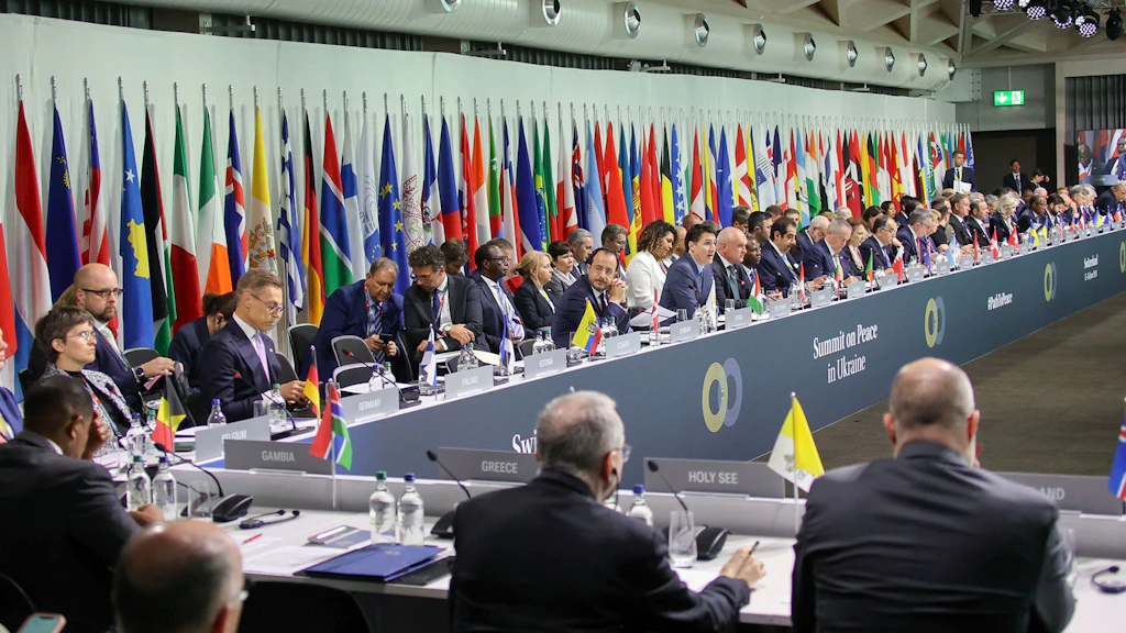 La sala plenaria della conferenza di alto livello sulla pace in Ucraina, con le bandiere di tutti gli  Stati e le organizzazioni partecipanti sullo sfondo.