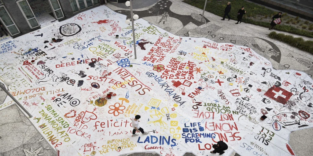 Vista dall’alto di un murale sul pavimento, su cui sono dipinte parole colorate. 