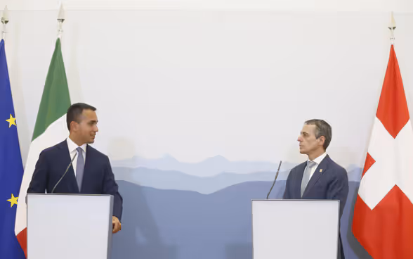 Il consigliere federale Cassis e il ministro degli Esteri italiano Luigi Di Maio siedono ciascuno dietro un leggio. Sullo sfondo si vedono le bandiere della Svizzera, dell'Italia e dell'UE.