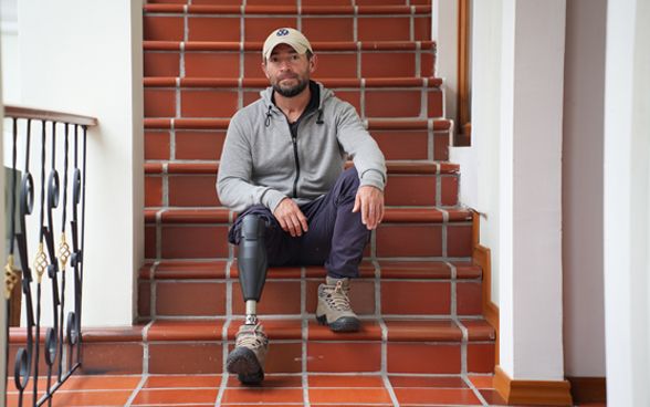 Andrés Betancourt è seduto su una scalinata. Indossa una protesi alla gamba.