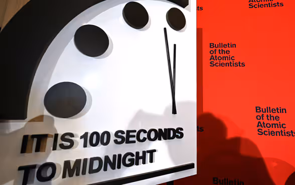 Un orologio bianco segna 100 secondi alla mezzanotte.