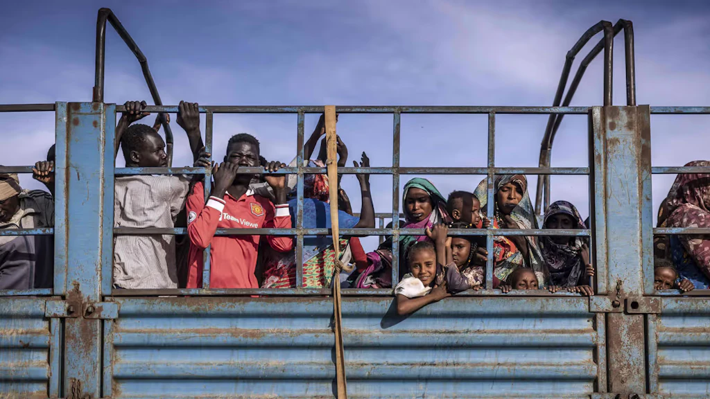 Donne, uomini e bambini sudanesi sul retro di un camion blu.