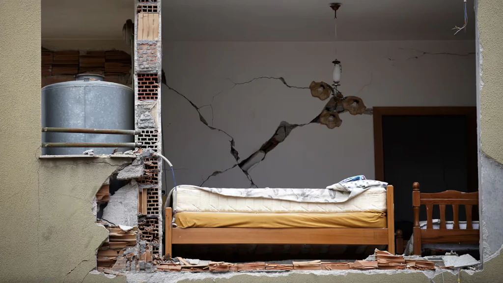 Il terremoto ha aperto un buco nella facciata di un edificio residenziale attraverso il quale si vede un letto.