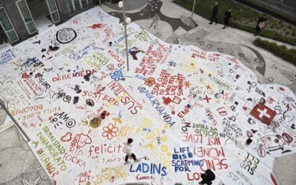 Vista dall’alto di un murale sul pavimento, su cui sono dipinte parole colorate.
